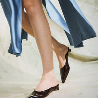 Faye Brown Crinkled Patent Leather Mules, , styled with a flowing blue dress - POEVE Collection
