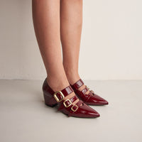Nova Cherry Red Crinkled Patent Leather Heel Shoes with Metal Buckles, worn on bare legs - POEVE Collection