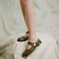 Maris Green Crinkled Patent Leather Mule, styled with a short black textured skirt - POEVE Collection