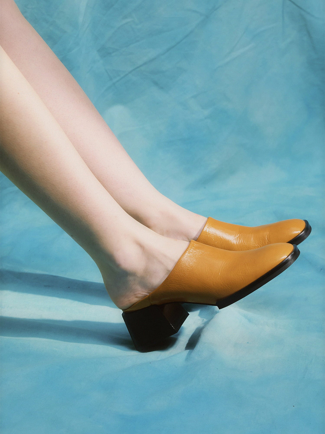 Robin Caramel Crinkled Patent Leather Heel Mules, worn on bare legs - POEVE Collection
