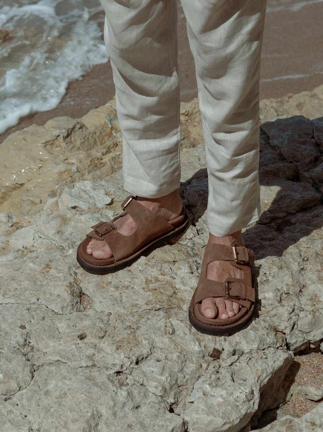 Rory Brown Crust Leather Mules with Metal Buckles, styled with beige linen trousers - POEVE Collection
