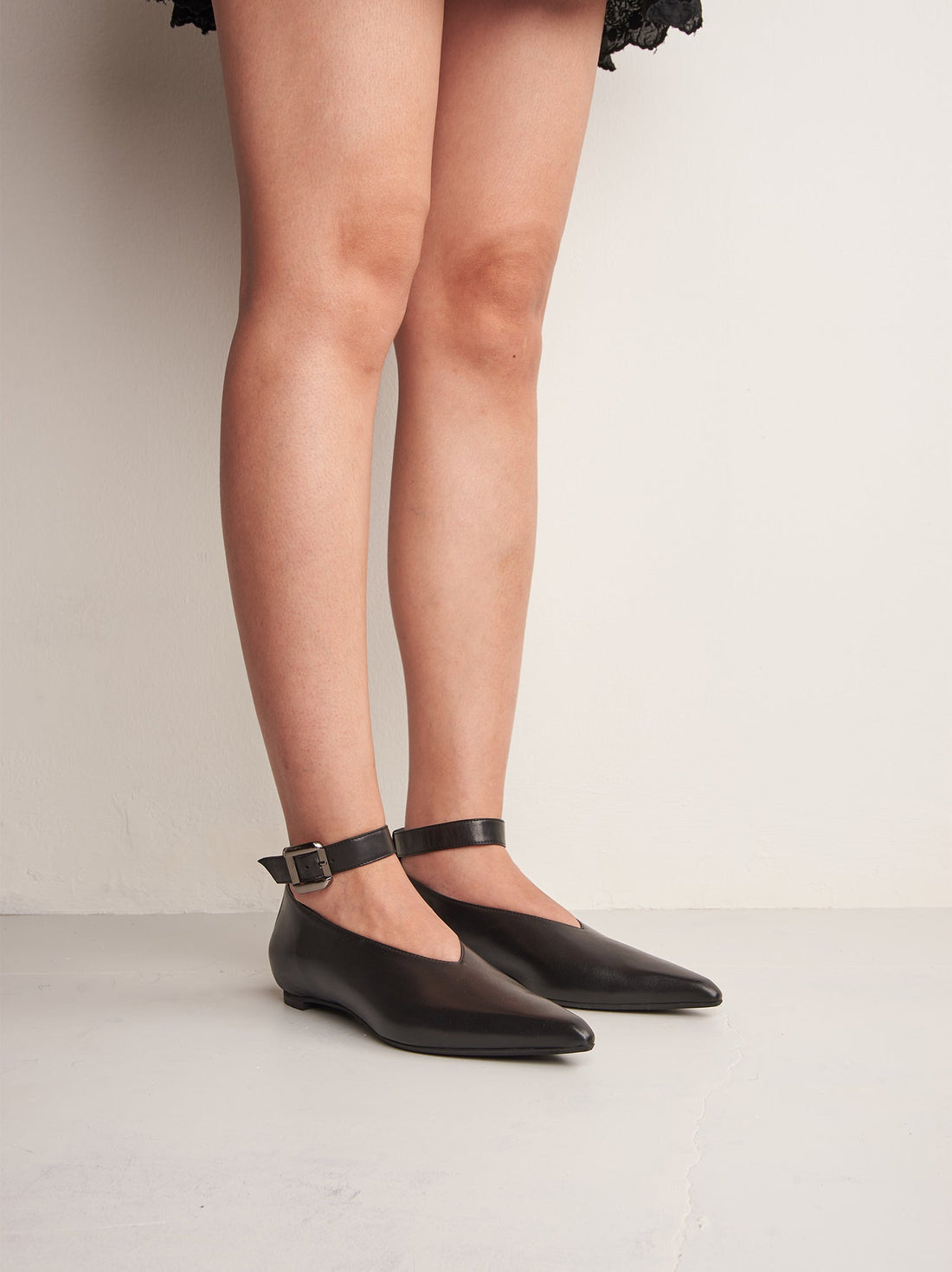 Stevie Black Leather Flat Shoes with Metal Buckle, worn on bare legs - POEVE Collection