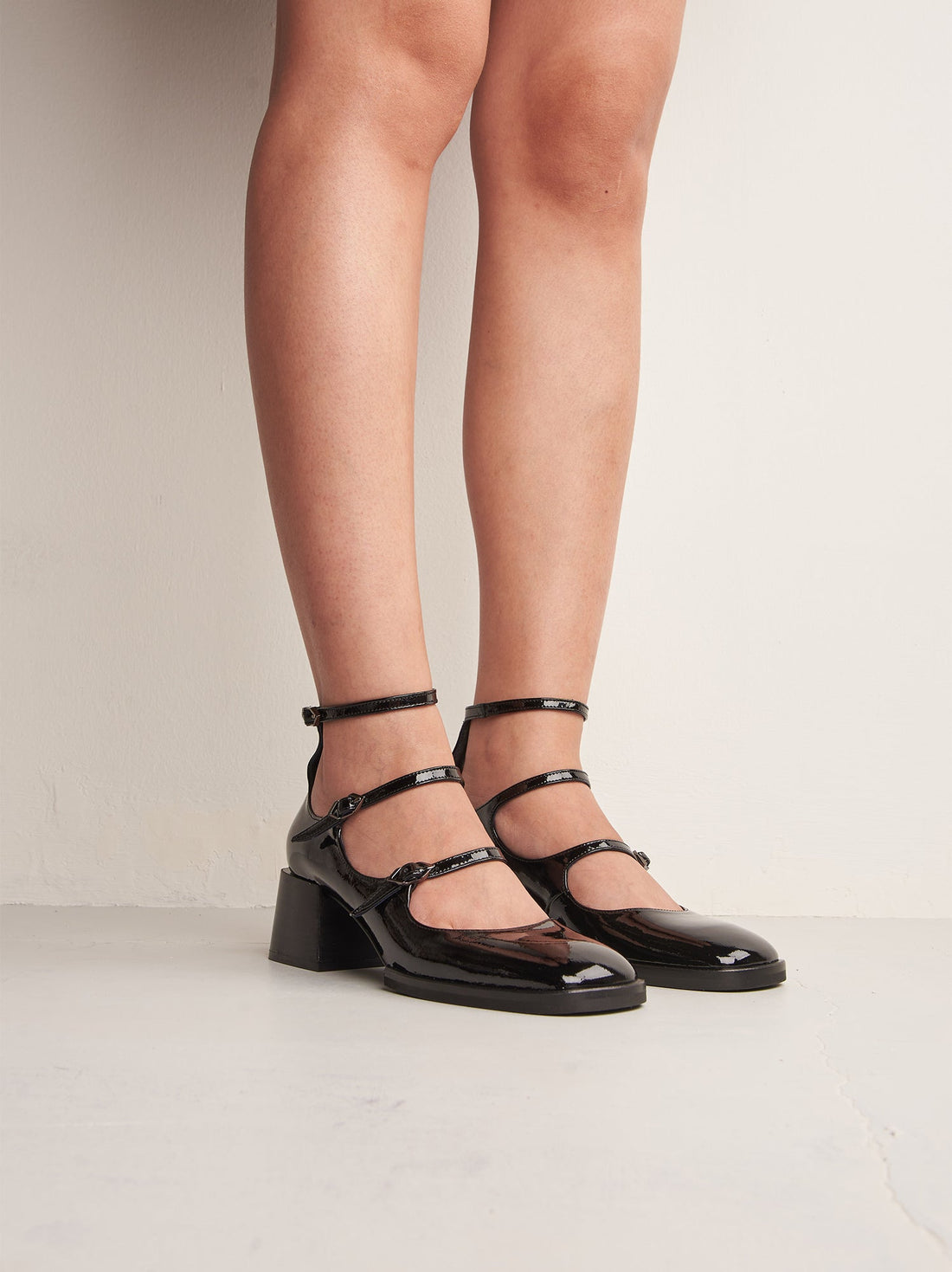 Maven Black Patent Leather Heel Shoes with Metal Buckles, worn on bare legs - POEVE Collection