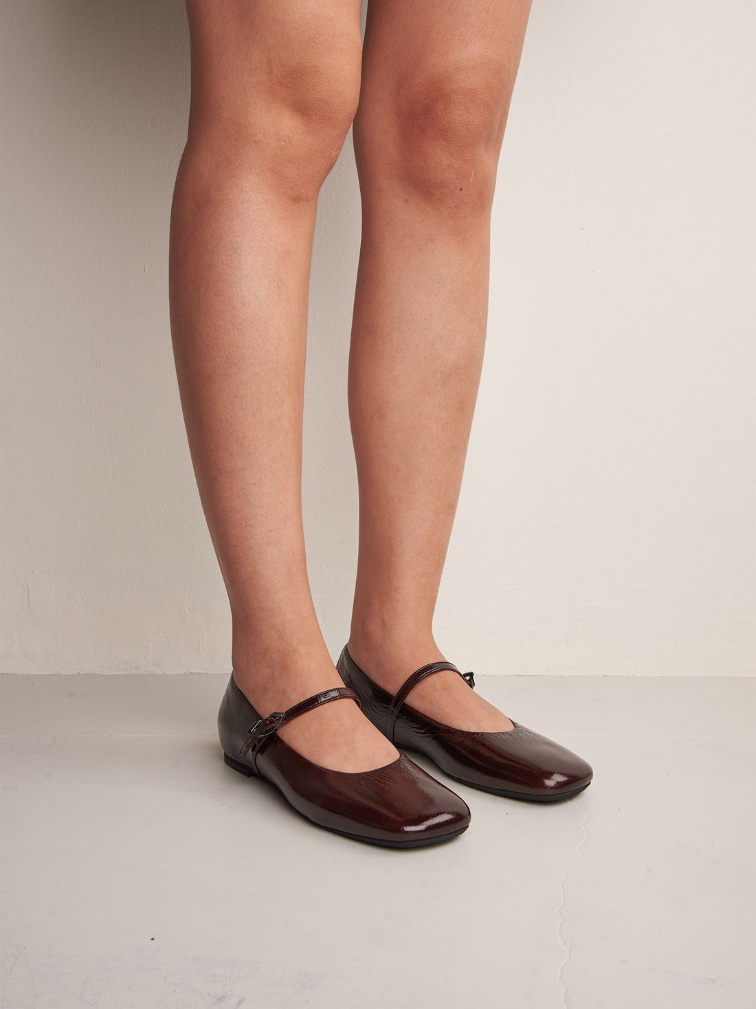 Aurora Dark Brown Crinkled Patent Leather Ballerinas, worn on bare legs - POEVE Collection