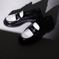 Ollie Black and White Brushed Leather Penny Loafers displayed under a dramatic spotlight, casting bold shadows on a minimalist grey surface - POEVE Collection