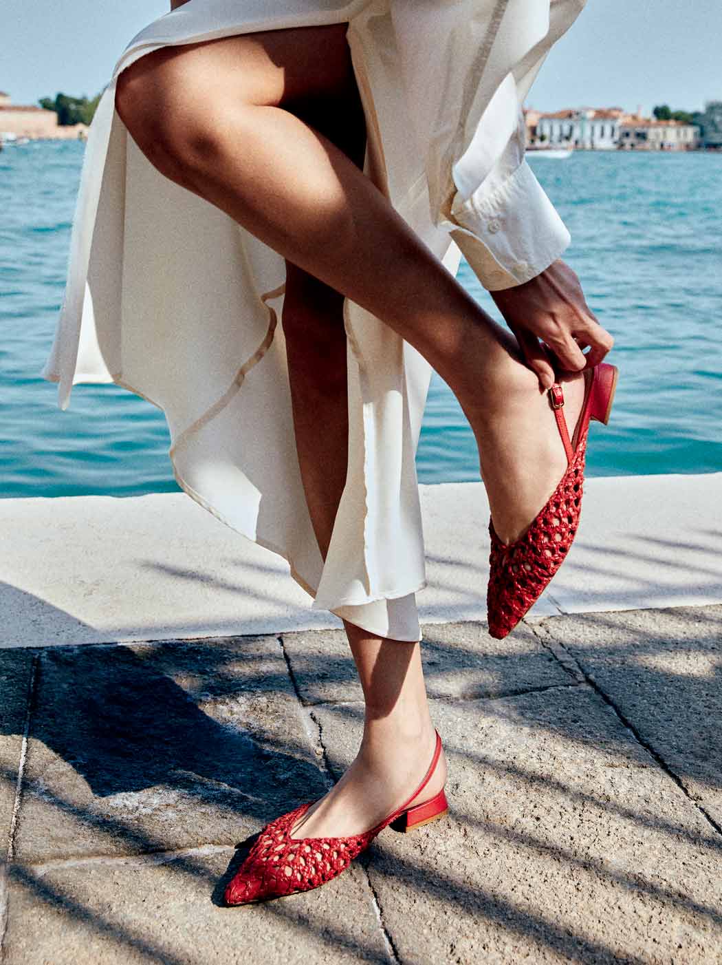 Fannie Red Vegan Hand-Woven Leather Slingback Sandals, styled with a flowing white dress - POEVE Collection