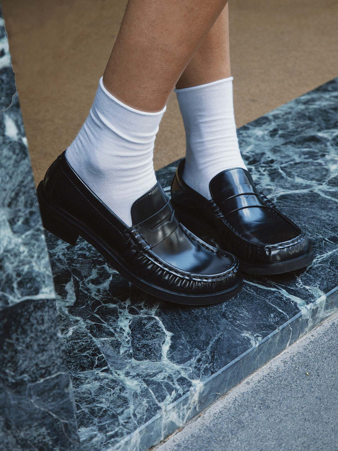 Vera Black Brushed Leather Loafers, styled with crisp white socks and worn on green-veined marble steps - POEVE Collection